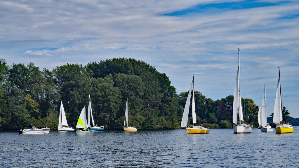 Absegeln 2025 am 20. September 2025. Die Segler*innen des Plöner Sees treffen sich im Hellock und machen sich auf nach Ascheberg. Unser 2. Vorsitzende begrüßt unsere Gäste vom Motorboot.